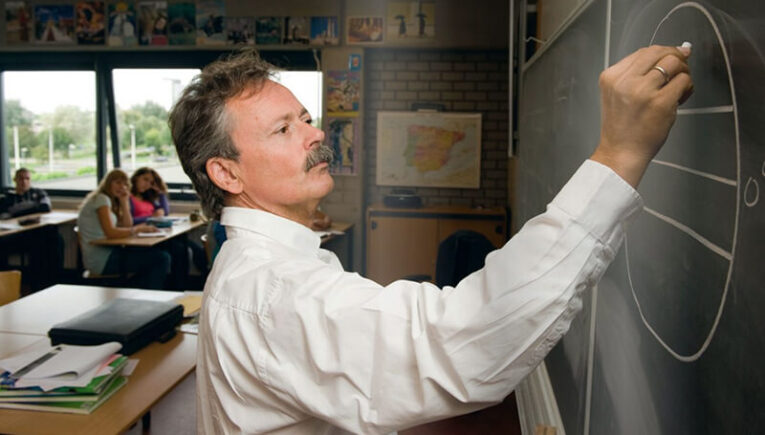 Docent Peter Teitler tekent met krijt op schoolbord