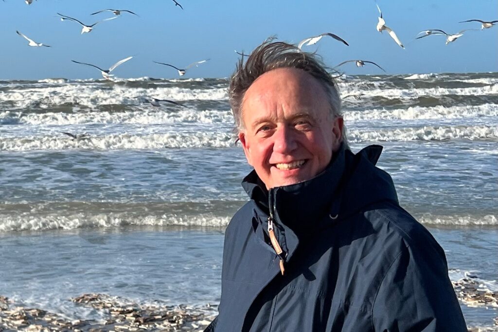 Portretfoto Menno Gaijkema met op de achtergrond de zee en vogels